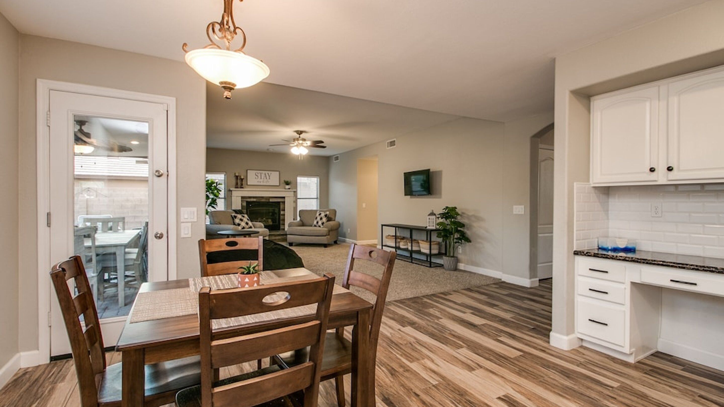 A spacious living area with a fireplace, a dining table with chairs, and a kitchen with white cabinets.