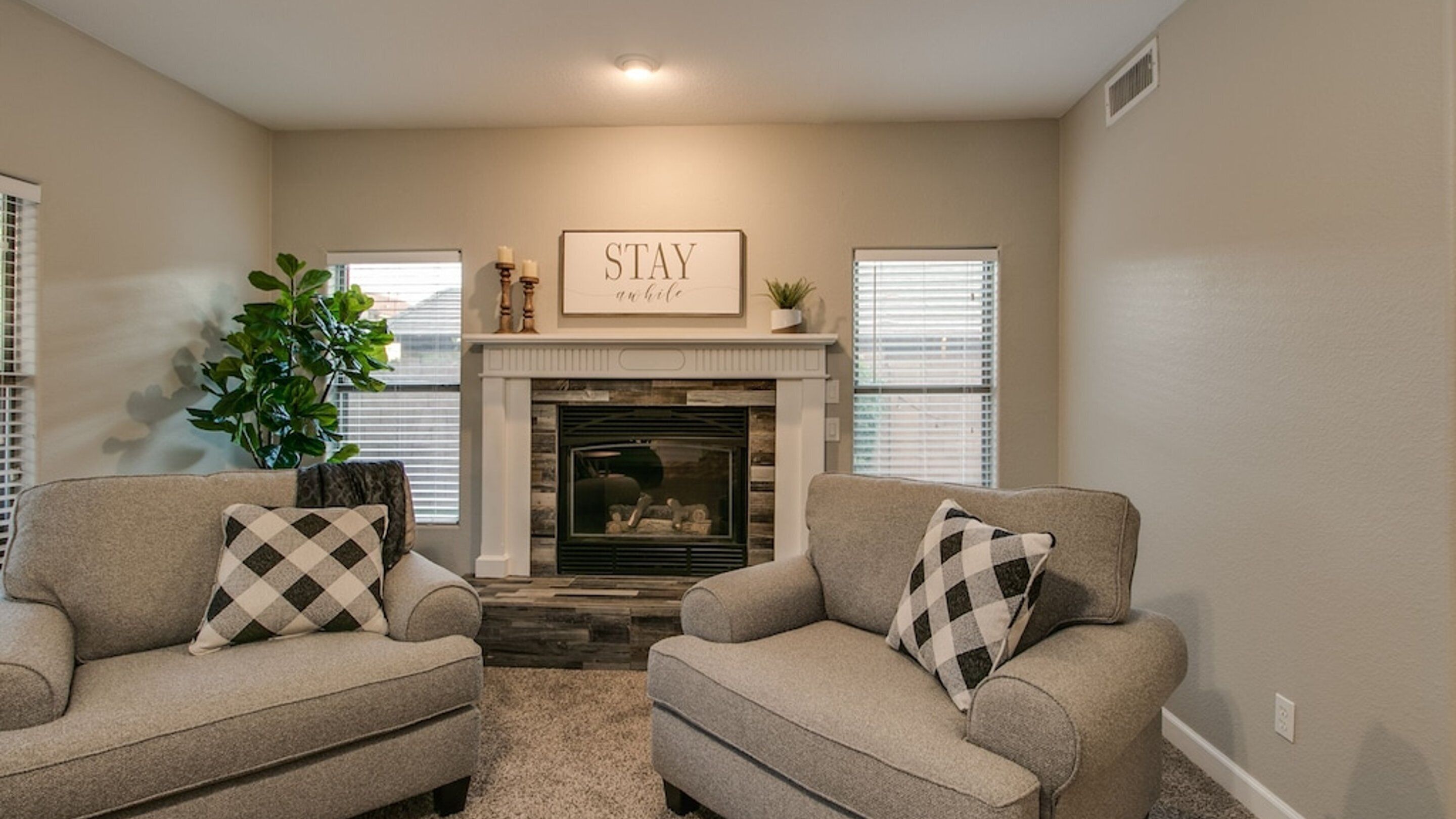 A living room with two armchairs, a fireplace, and a sign that reads "STAY calm."