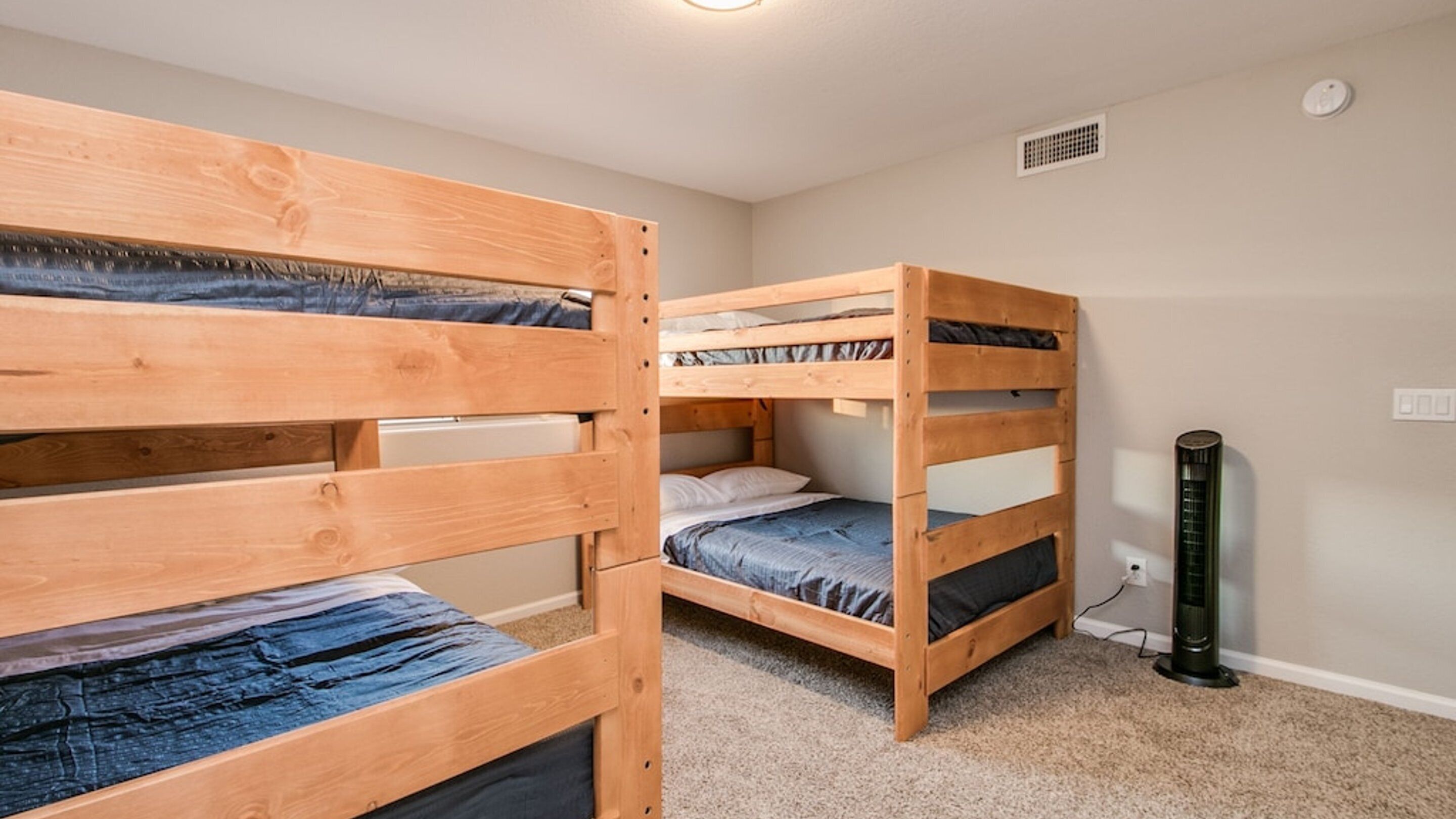 A room with two bunk beds, a heater, and a power outlet on the wall.