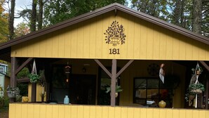 A yellow building with the number 181, featuring a porch with hanging plants and a stone wall at the front. - Boho shabby chic shack In beautiful resort (Newland)