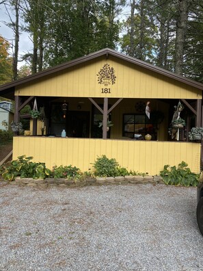 A yellow building with the number 181 on the front, surrounded by plants and trees.