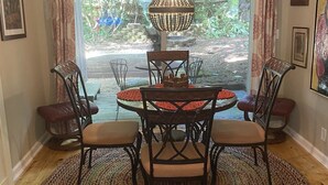 A dining area with a round table, four chairs, a patterned rug, and a hanging light fixture. - Boho shabby chic shack In beautiful resort (Newland)