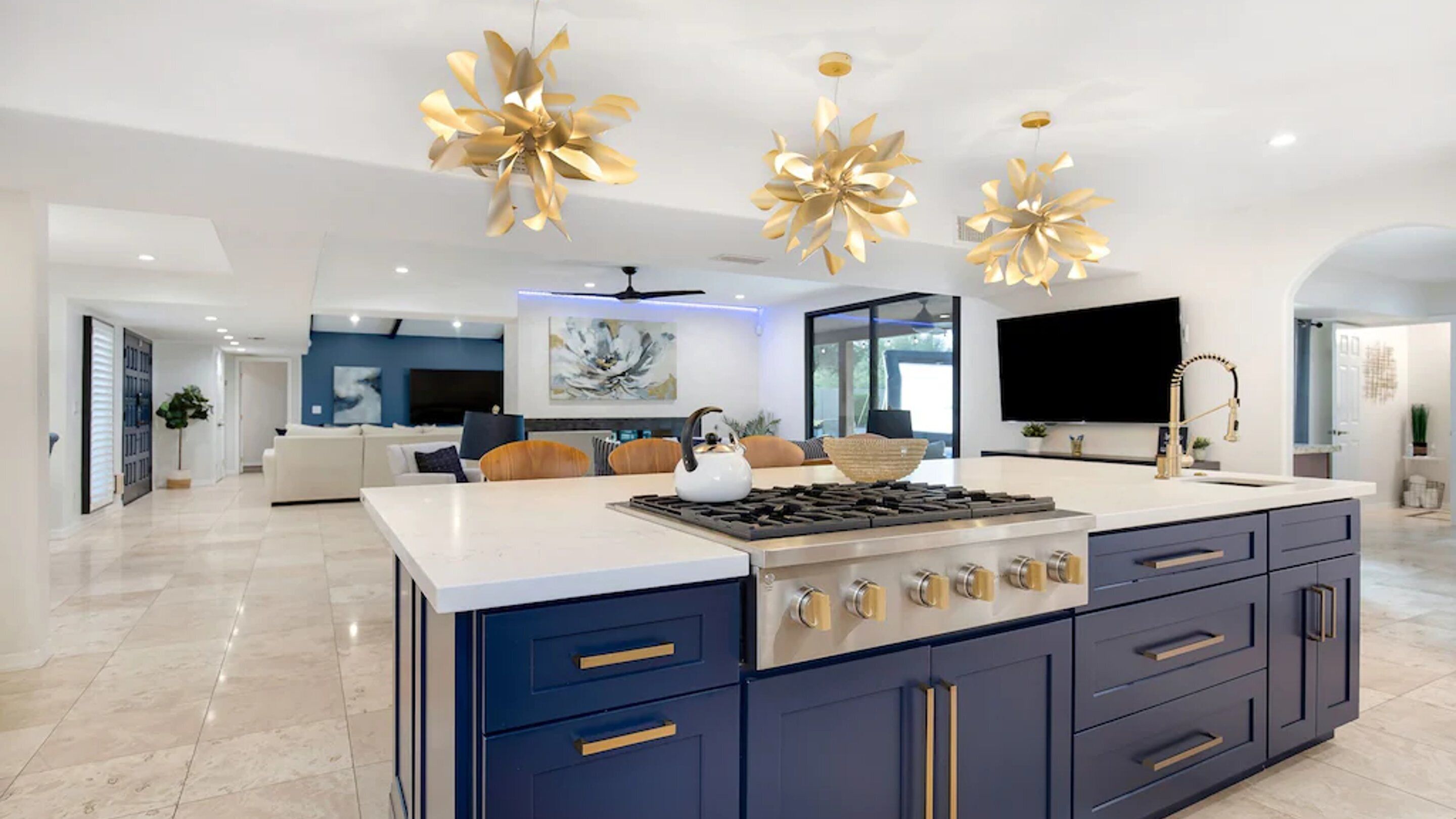 A modern kitchen with a large island, built-in appliances, and decorative gold ceiling lights.