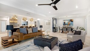 A spacious living room with a modern sofa, a coffee table, and a dining area with chairs and a table. - Stunning Vacation Dream Home W/backyard Paradise! (Scottsdale)