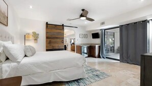 A modern bedroom with a large bed, a ceiling fan, and a sliding glass door leading to a balcony. - Stunning Vacation Dream Home W/backyard Paradise! (Scottsdale)