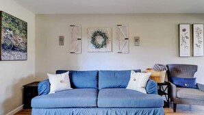 Un salon avec un canapé bleu, deux coussins à rayures et une table basse en bois.