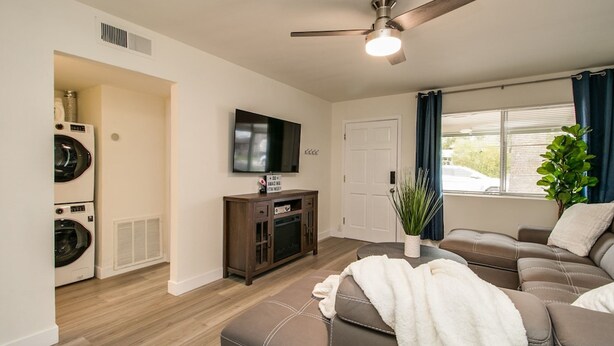 A living room with a ceiling fan, a television, a sofa, and a window with curtains. - Remodeled 2 Bdrm w/ Yard in Old Town Scottsdale! (Scottsdale)