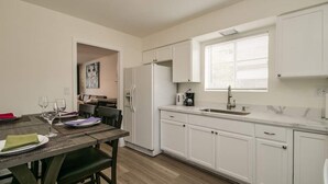 A compact kitchen with white cabinets, a built-in oven, and a window with blinds. - Remodeled 2 Bdrm w/ Yard in Old Town Scottsdale! (Scottsdale)