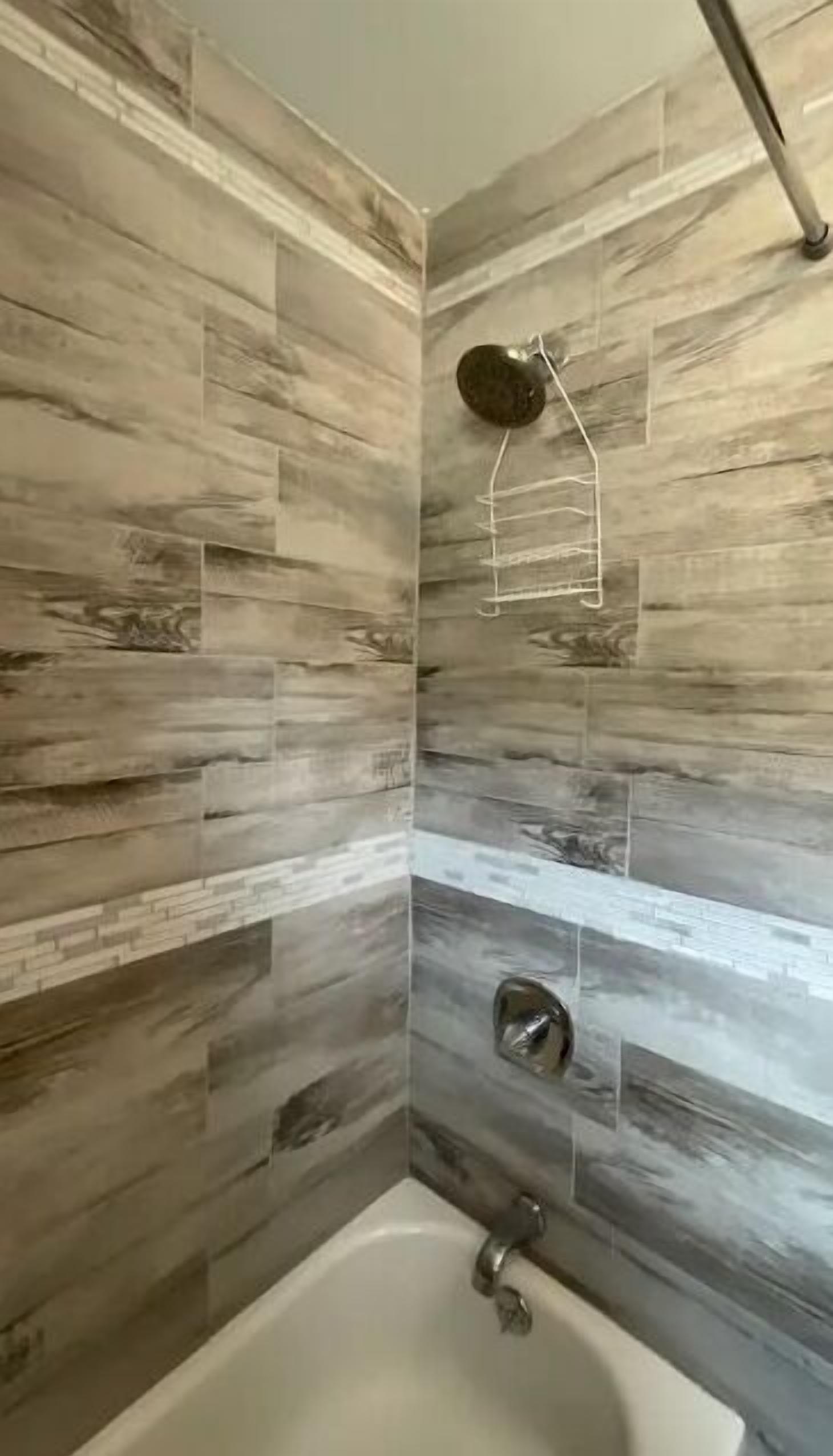 Een badkamer met een bad, douche en handdoekhouder.
