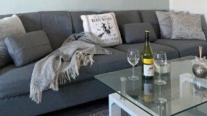 A modern living room with a grey sofa, a glass coffee table, and a tiger artwork on the wall.