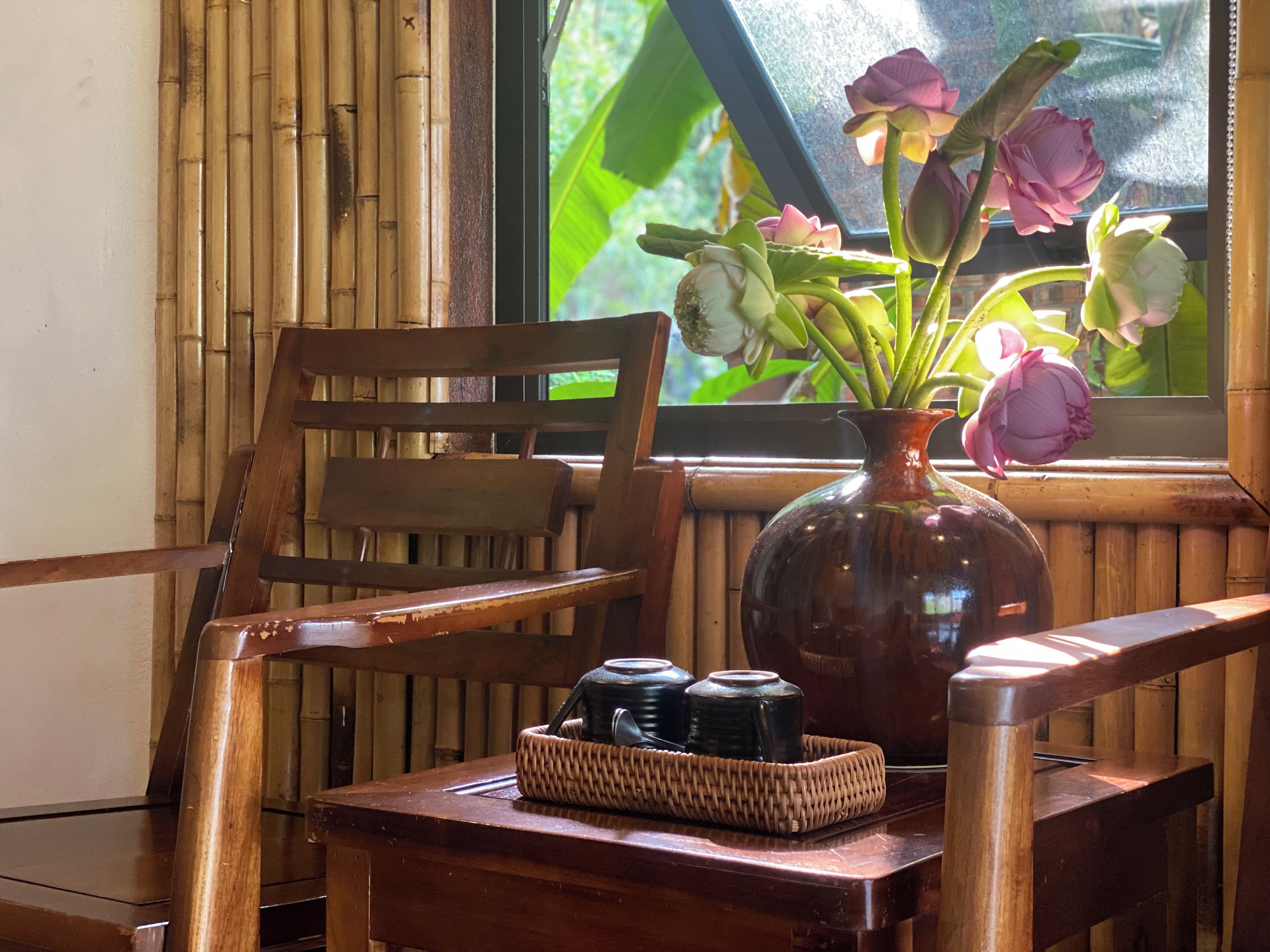 A wooden chair and table with a vase of flowers and a woven basket.