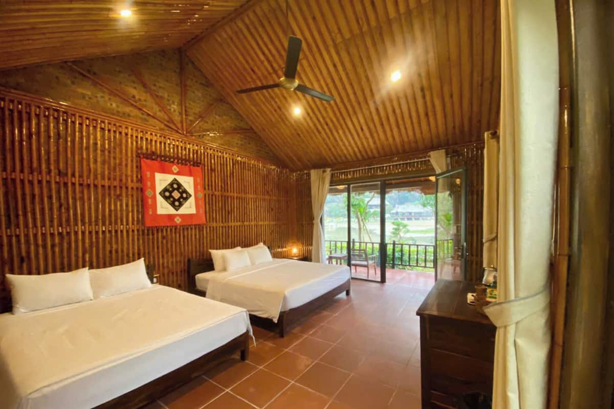 A room with two beds, a ceiling fan, and a view of the outdoors.