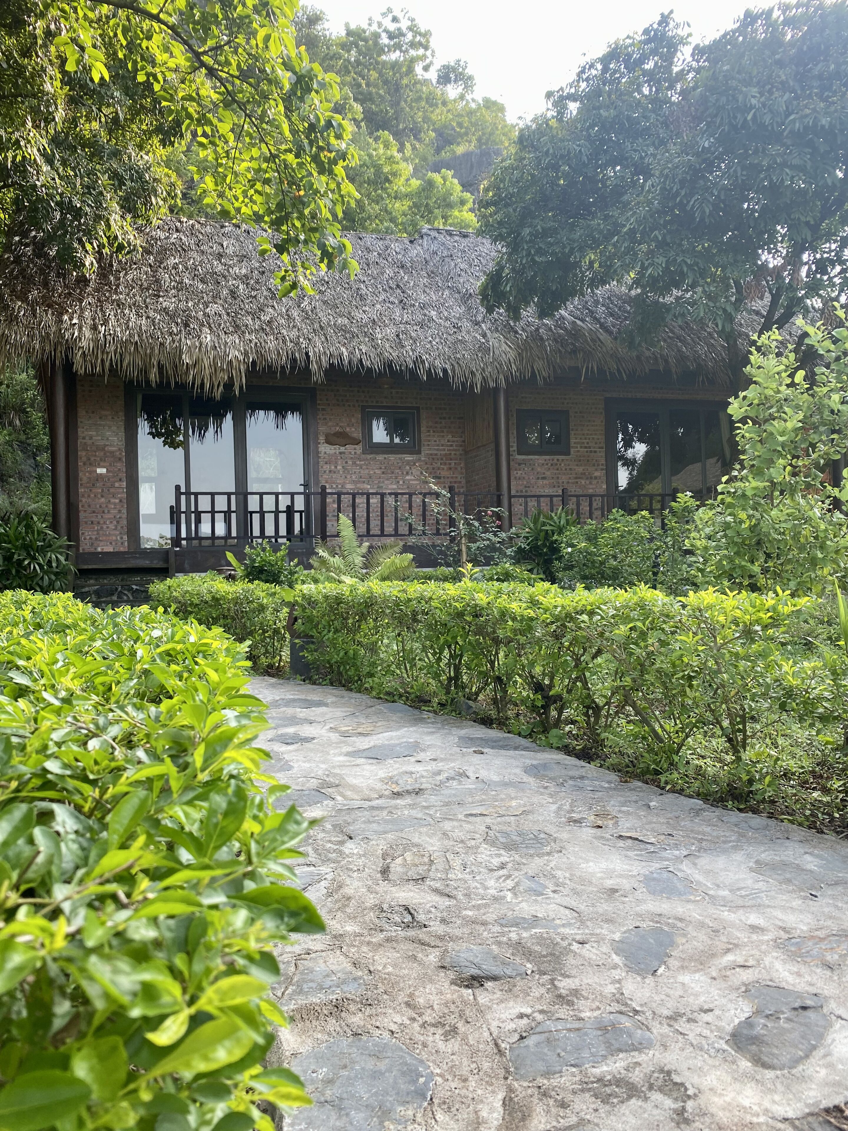 A rustic building with a thatched roof, brick walls, and large windows.