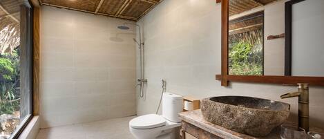 A bathroom with a shower, toilet, and a large stone sink.