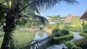 A serene garden with a pond, a stone bridge, and lush greenery.