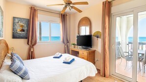 A hotel room with a bed, a ceiling fan, a TV, a sliding glass door to a balcony, and a painting on the wall. - Puerta del mar 2 Mijas, Mijas Costa, Spain (Mijas Costa)