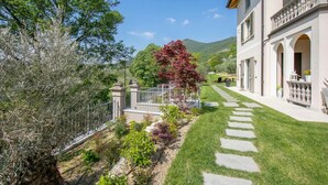 A well-maintained garden with a stone pathway leading to a building with a balcony. - Ricomilla-Ulivo -Balcony, Garden & Privat, Roè Volciano, Italy (Roè Volciano)