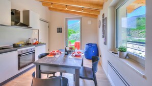 A modern kitchen with a dining area, wooden ceiling, and a view of greenery. - Ricomilla-Ulivo -Balcony, Garden & Privat, Roè Volciano, Italy (Roè Volciano)