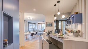 Une cuisine moderne dotée d’un îlot central, de luminaires suspendus et donnant sur l’espace repas.