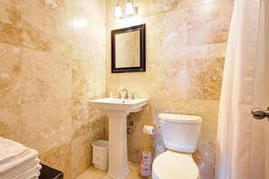 A bathroom with a sink, mirror, toilet, and a towel rack. - Wellington Inn by Hoco Hotels Collection (Stratford)