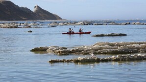 Una masa de agua tranquila con formaciones rocosas y una montaña distante.