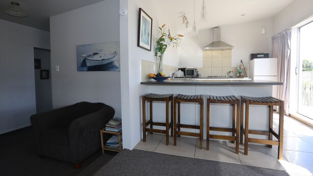 Una cocina moderna con una isla central, taburetes de bar, zona de comedor y sofá.