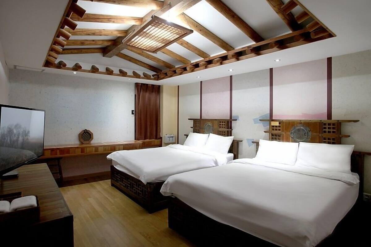 Una habitación de hotel con dos camas, televisión y techo de madera.