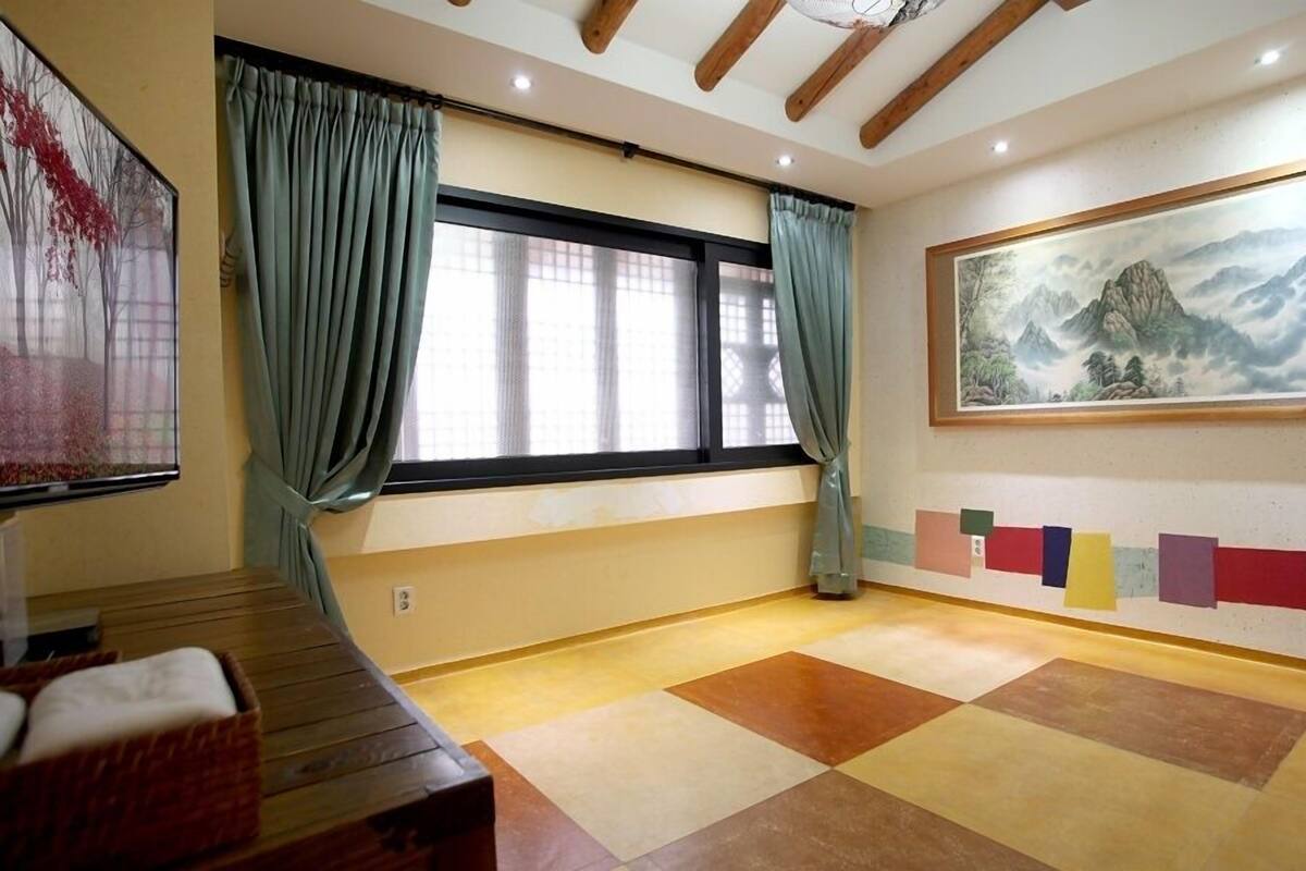 Una habitación con un ventanal grande, un cuadro en la pared y un suelo a cuadros.