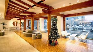 Un vestíbul espaiós amb bigues de fusta, un arbre de Nadal i vista a cotxes estacionats a l'exterior.