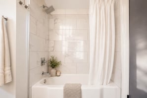 A modern bathroom with a bathtub, a showerhead, a towel rack, and a potted plant. - Villa w/heated pool & spa (Phoenix)