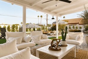 A covered outdoor seating area with white furniture, a pool, and umbrellas. - Villa w/heated pool & spa (Phoenix)