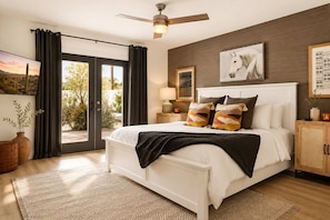 A bedroom with a bed, a ceiling fan, a nightstand, a lamp, a window with curtains, and a view of the outdoors. - Villa w/heated pool & spa (Phoenix)