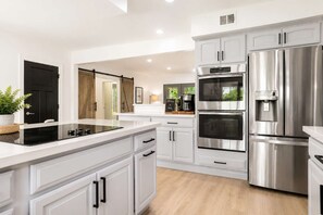 A modern kitchen with stainless steel appliances, white cabinetry, and a central island. - Villa w/heated pool & spa (Phoenix)