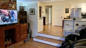 Uma sala de estar moderna com uma TV de tela plana, armários de madeira e um vaso com flores secas.