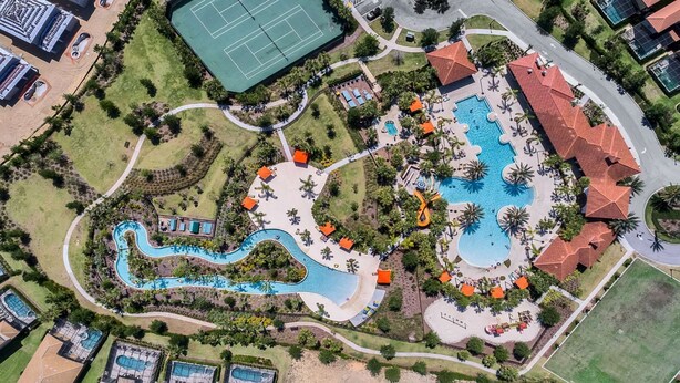 Vue aérienne d’un complexe hôtelier doté d’une grande piscine centrale, de plusieurs piscines plus petites et de courts de tennis.