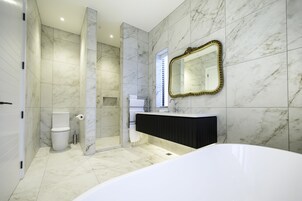 Un baño moderno con una bañera grande, un tocador con espejo y una zona de ducha.