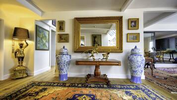 A spacious room with a large mirror, ornate vases, and a decorative statue.