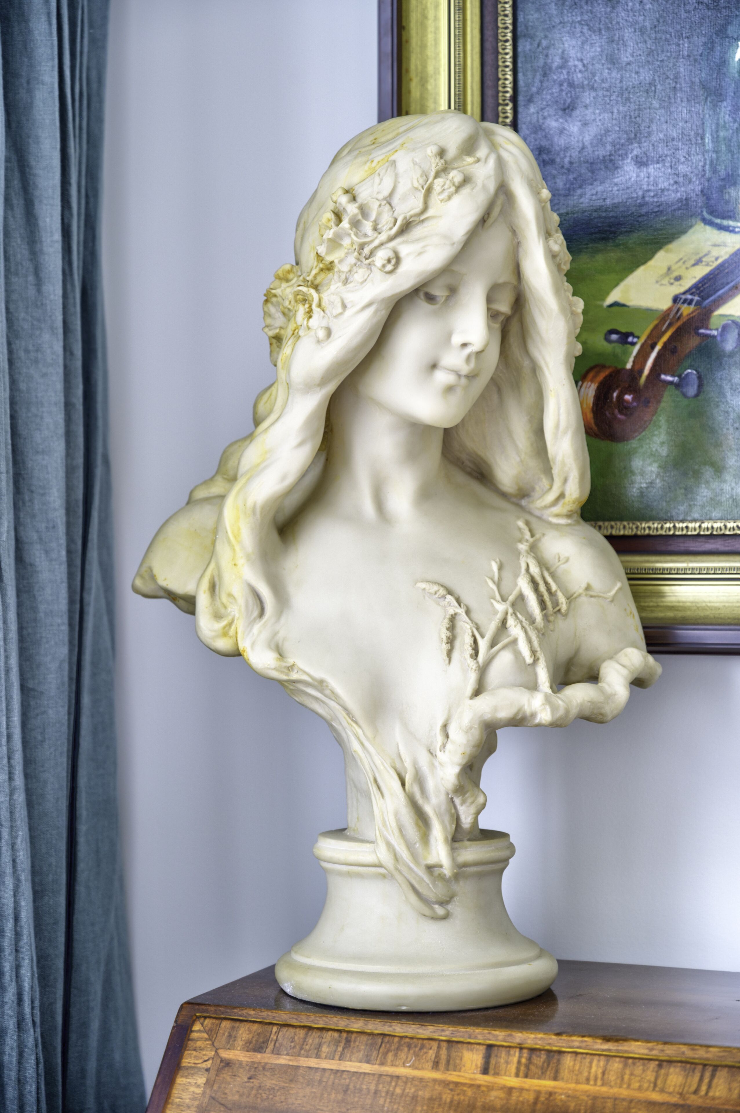 A bust sculpture on a wooden pedestal.