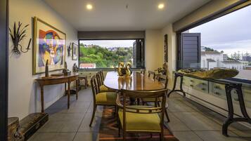 A dining area with a large table, chairs, and a view of the city through a large window.