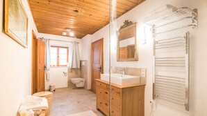Un baño con armarios de madera, un lavabo, un espejo, un perchero para toallas y un inodoro.
