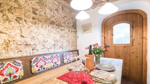 Un comedor rústico con pared de piedra, puerta de madera y decoración mural colorida.