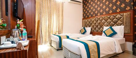 A hotel room with two beds, a desk with a telephone, a mirror, and a window with curtains.