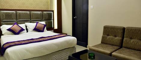 A hotel room with a large bed, a dark door, and a sofa.