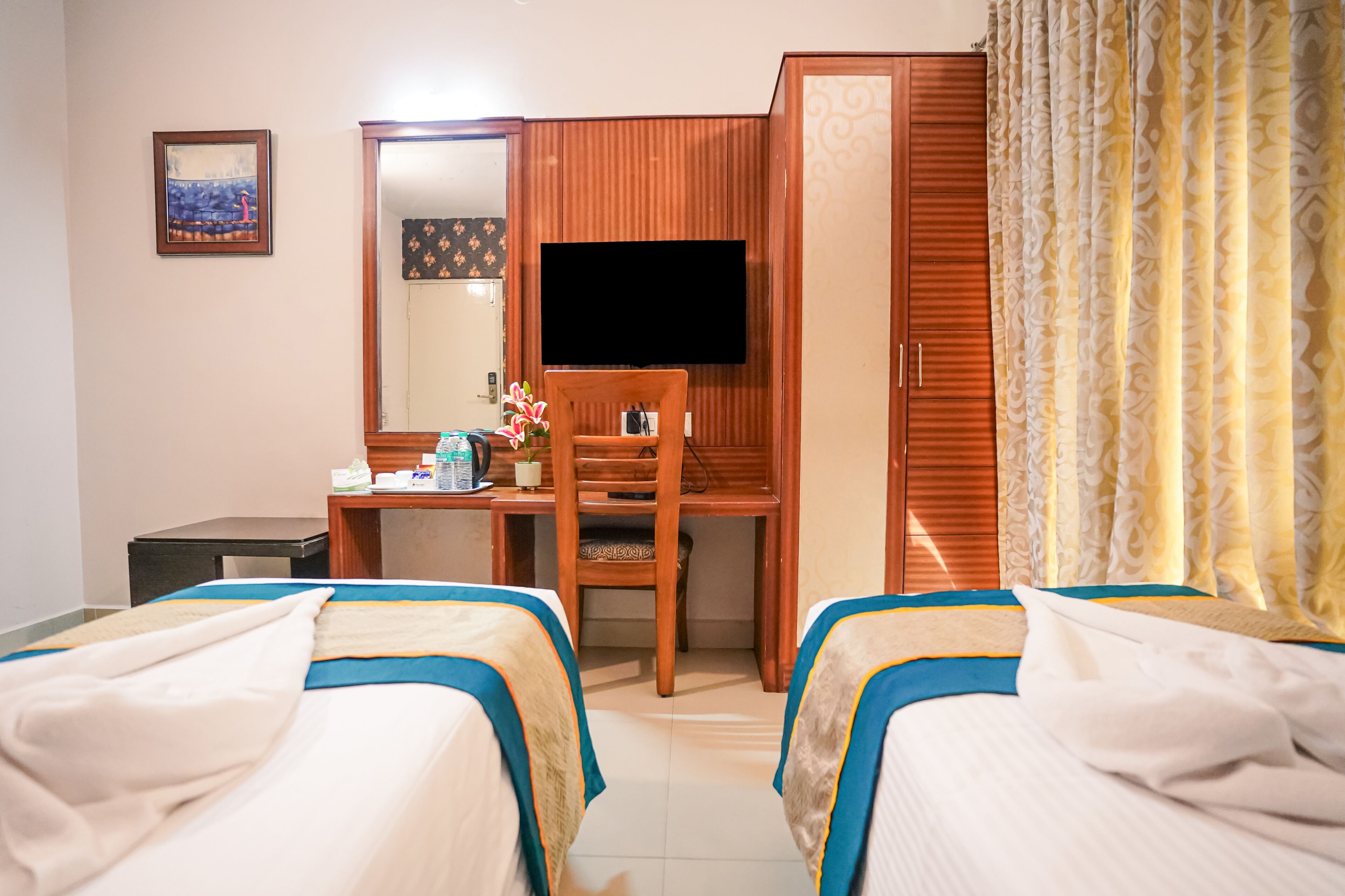 Une chambre d’hôtel avec deux lits, un bureau, une chaise, une télévision et une armoire.
