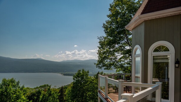 Une terrasse en bois avec une rambarde donnant sur un lac et des montagnes.