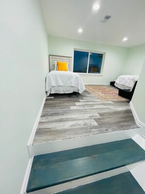 A bedroom with a bed, a window, and a staircase. - Best of Tides - Make family memories! (Galveston)