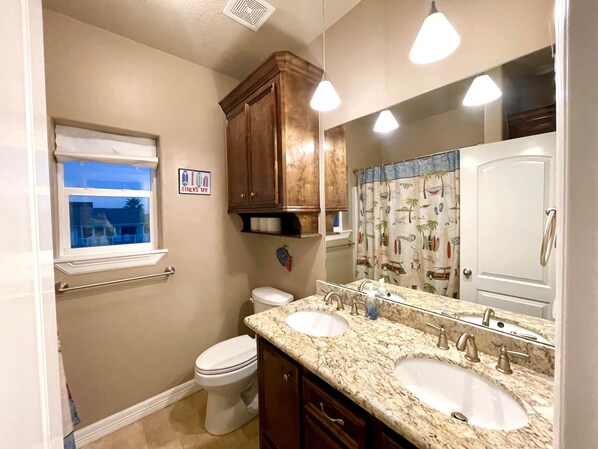 Une salle de bain avec deux lavabos, des toilettes, une fenêtre et un miroir.