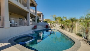 Une piscine avec un jacuzzi, une terrasse couverte et un escalier menant à un balcon.