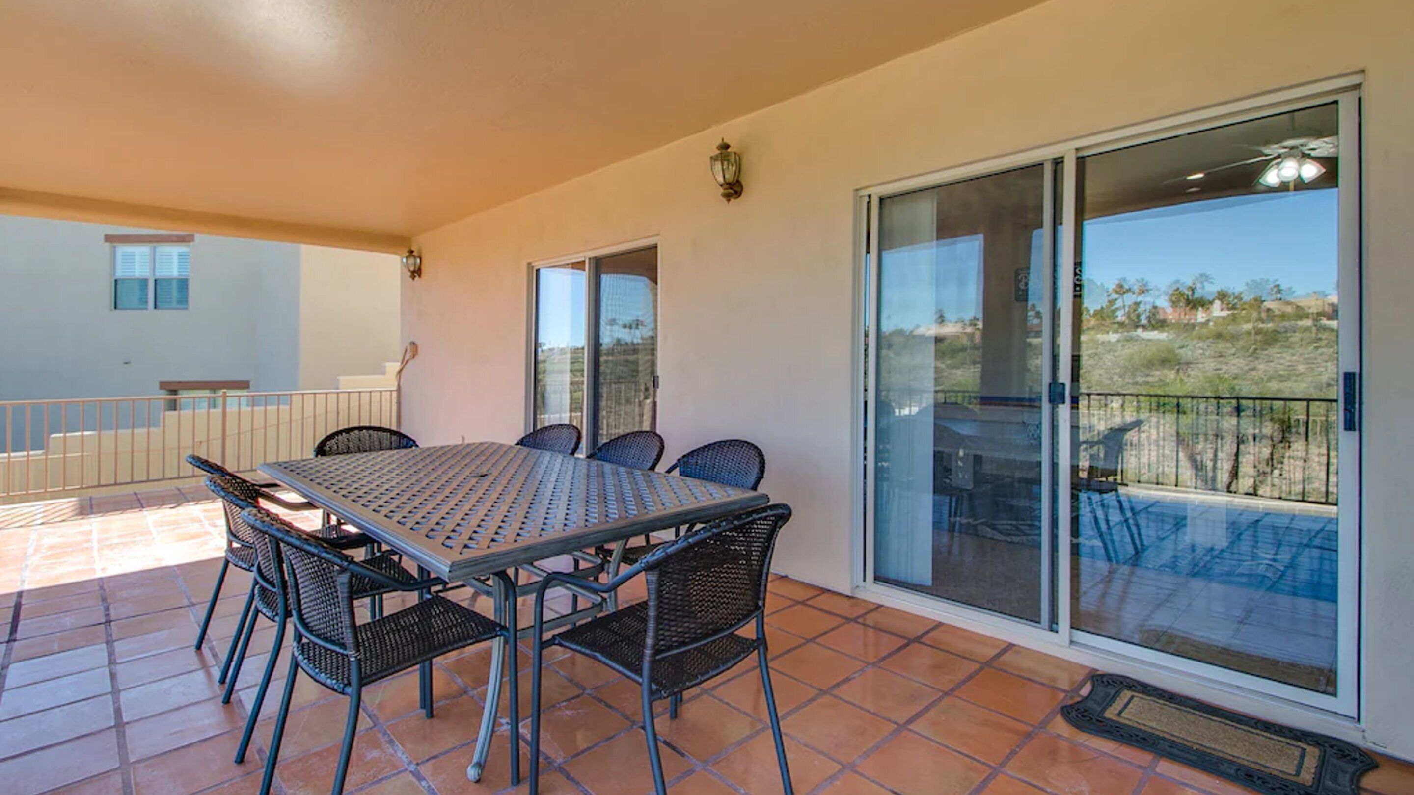 A patio with a table and chairs, a sliding glass door, and a view of the landscape.