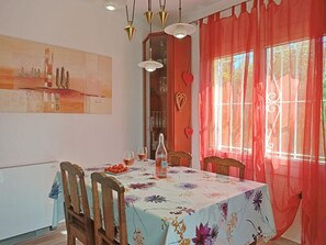 A dining area with a table set for two, a bottle of water, and a plate of fruit.